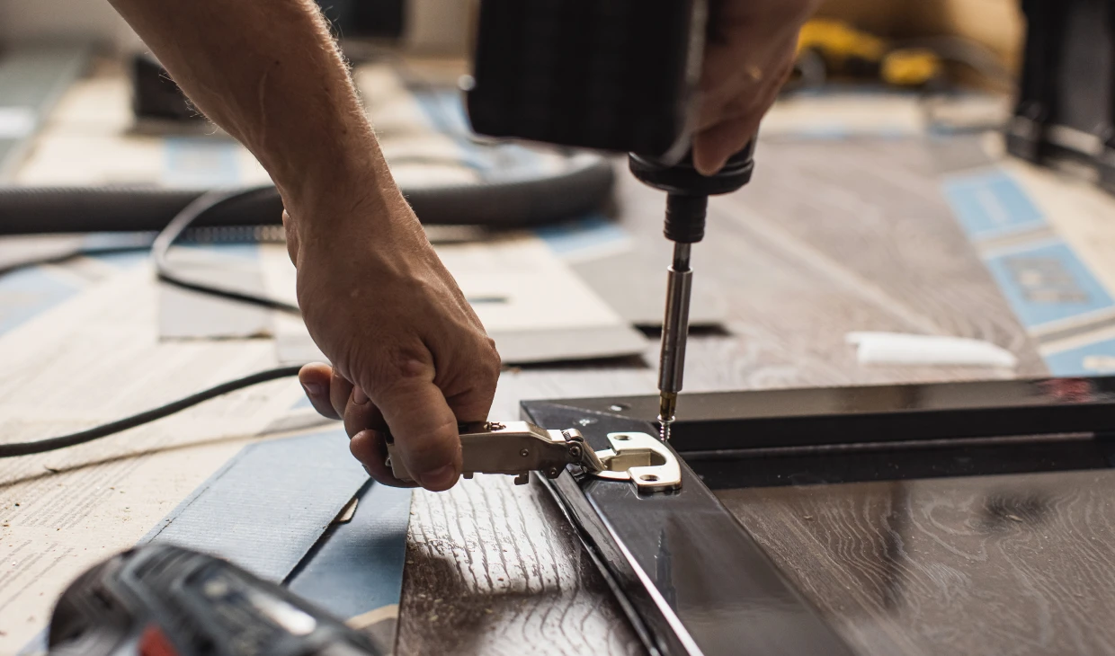 Hands working with screwdriver and hinge
