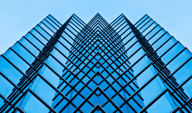 Symmetrical blue glass building against sky
